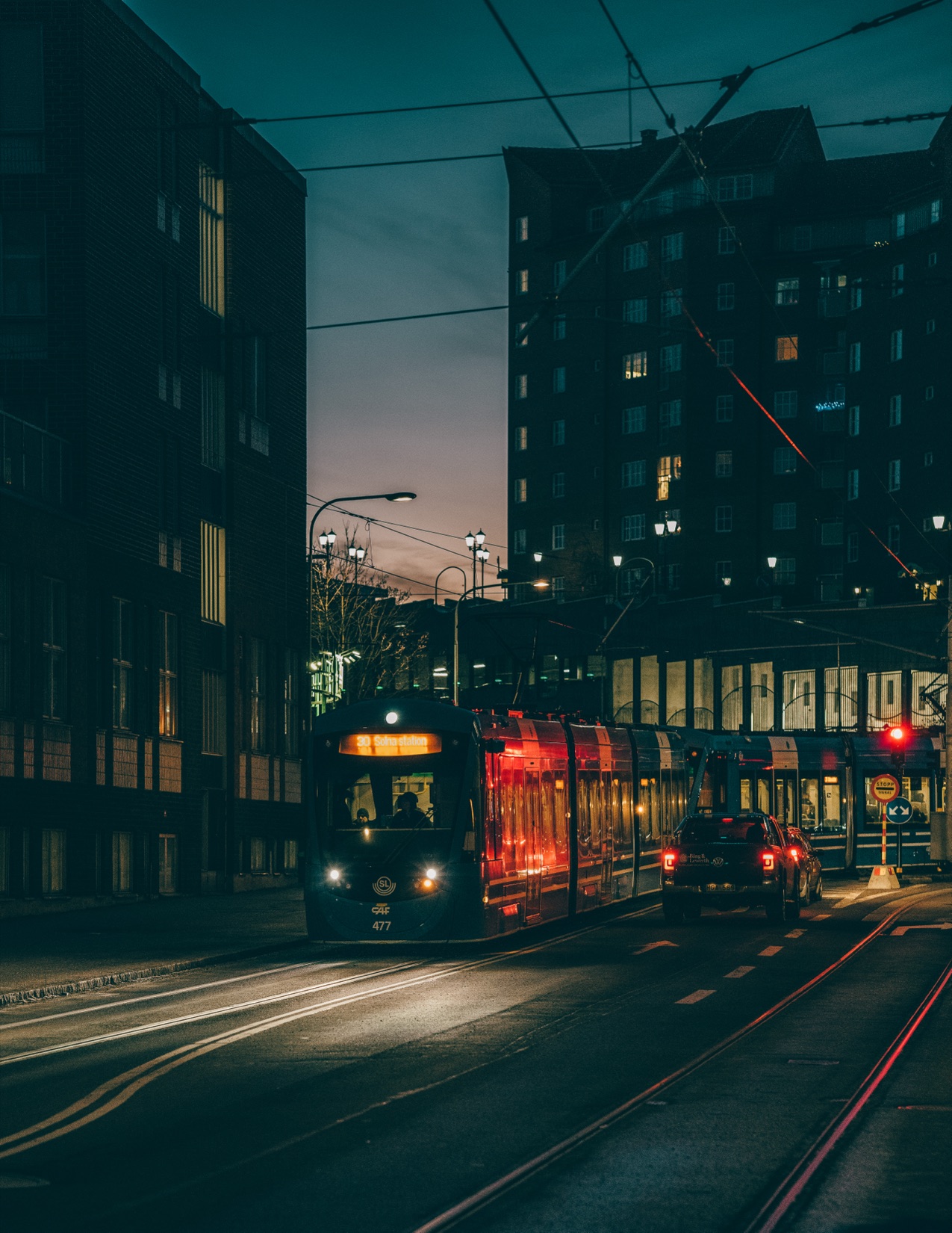 A red-lit tram moving through a dark blue city street