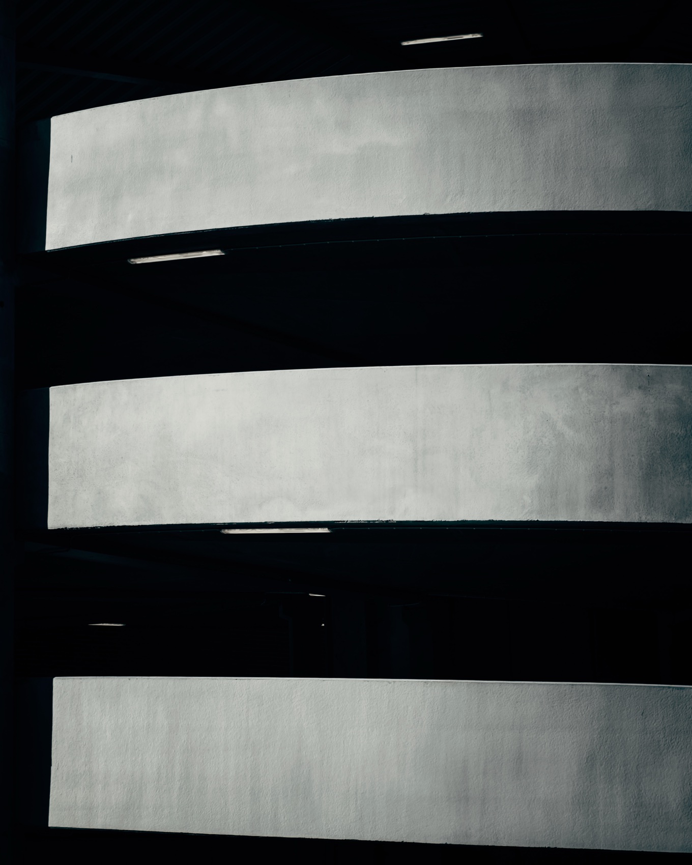 Minimal curved concrete bands floating against dark negative space